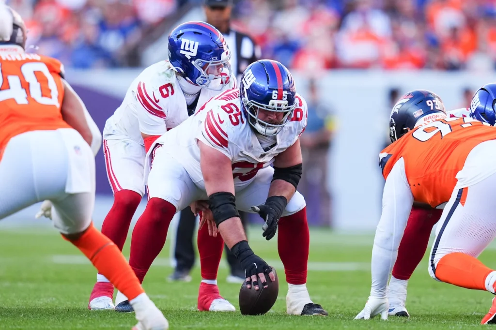 New York Giants guard Austin Schlottmann (65) snaps the ball to quarterback Jaxson Dart (6) against the Denver Broncos during an NFL football game Sunday, Oct. 19, 2025, in Denver. (AP Photo/Jack Dempsey)