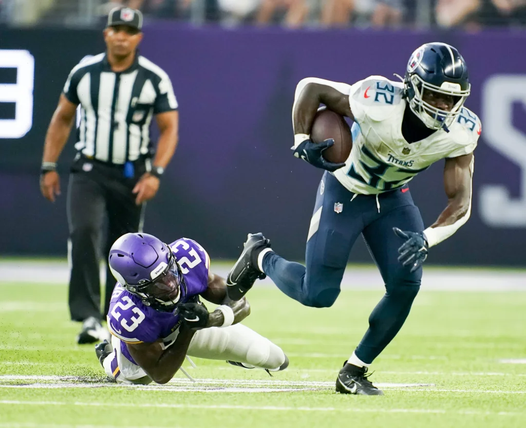 Tennessee Titans running back Tyjae Spears (32) slips past Minnesota Vikings cornerback Andrew Booth Jr. (23) to pick up a first down at U.S. Bank Stadium in Minneapolis, Minn., Saturday, Aug. 19, 2023.