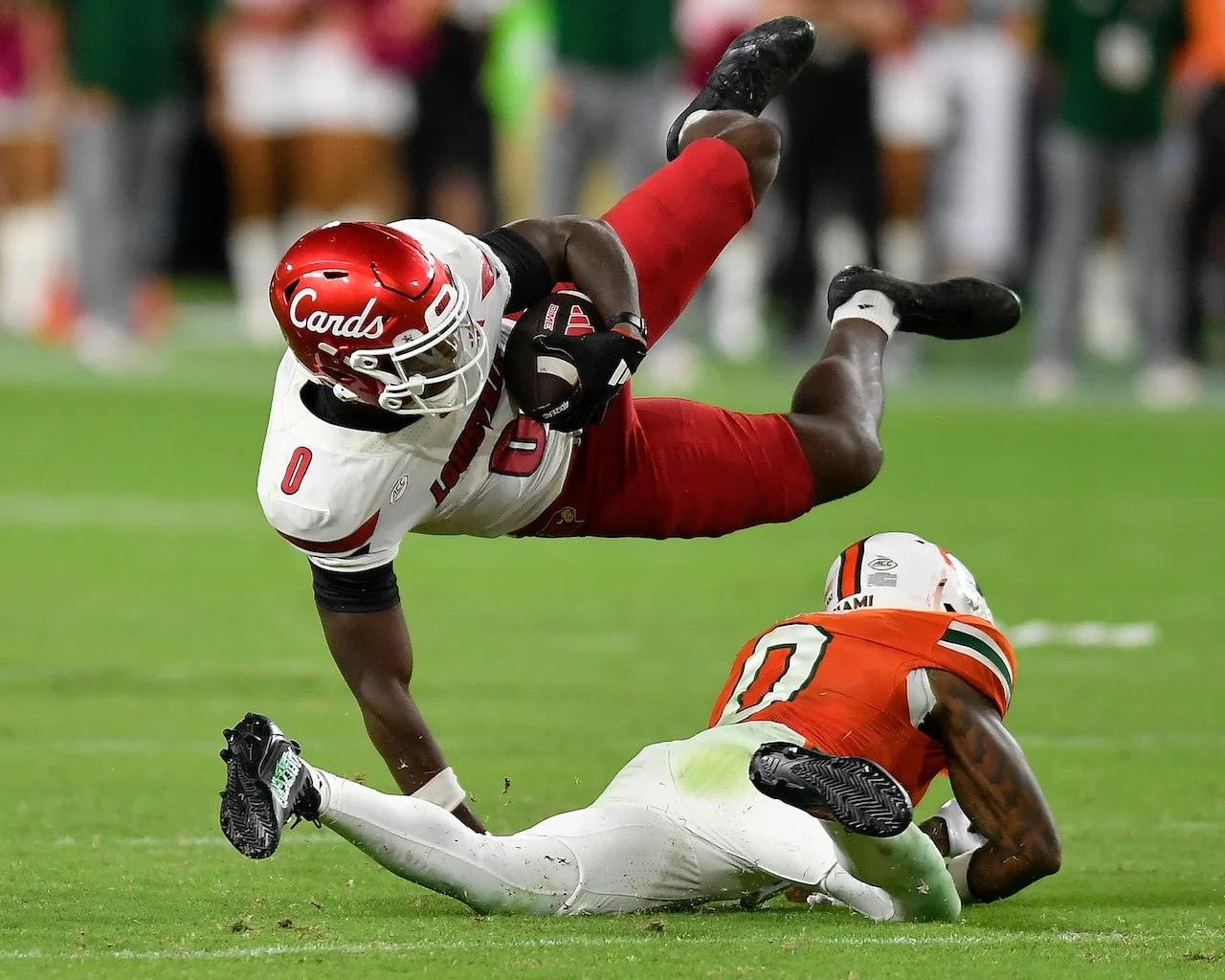 Louisville wide receiver Chris Bell, top, is tackled by Miami defensive back Keionte Scott, bottom, during the second half of an NCAA college football game, Friday, Oct. 17, 2025, in Miami Gardens, Fla. (AP Photo/Michael Laughlin)