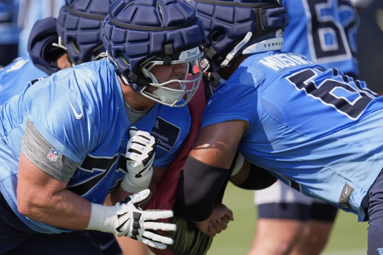 Tennessee Titans offensive linemen Peter Skoronski, left, and Sam Mustipher, right, run through a drill during practice at the team's NFL football training camp Thursday, July 24, 2025, in Nashville, Tenn. (AP Photo/George Walker IV)