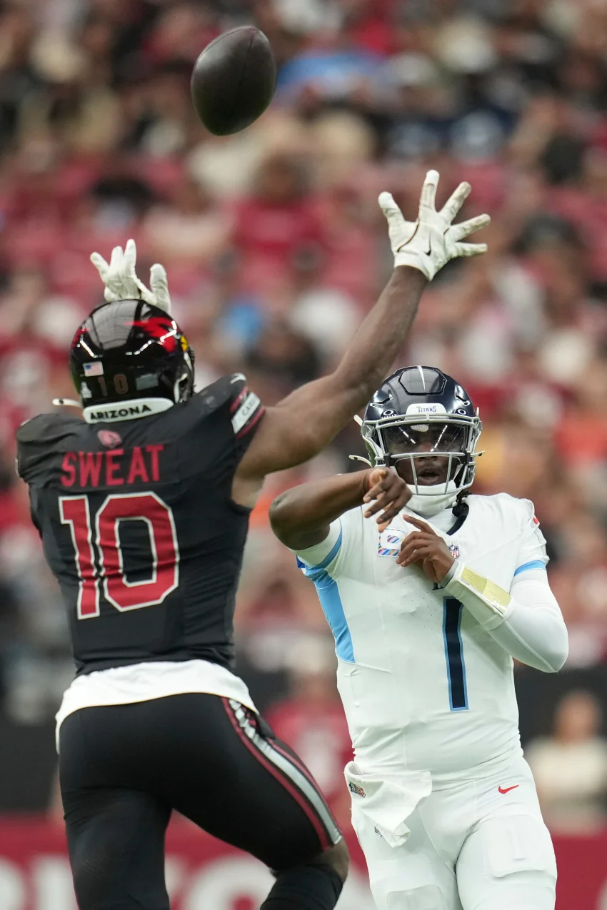 Tennessee Titans quarterback Cam Ward (1) throws a pass over Arizona Cardinals outside linebacker Josh Sweat (10) during the first half of an NFL football game Sunday, Oct. 5, 2025, in Glendale, Ariz. (AP Photo/Rick Scuteri)