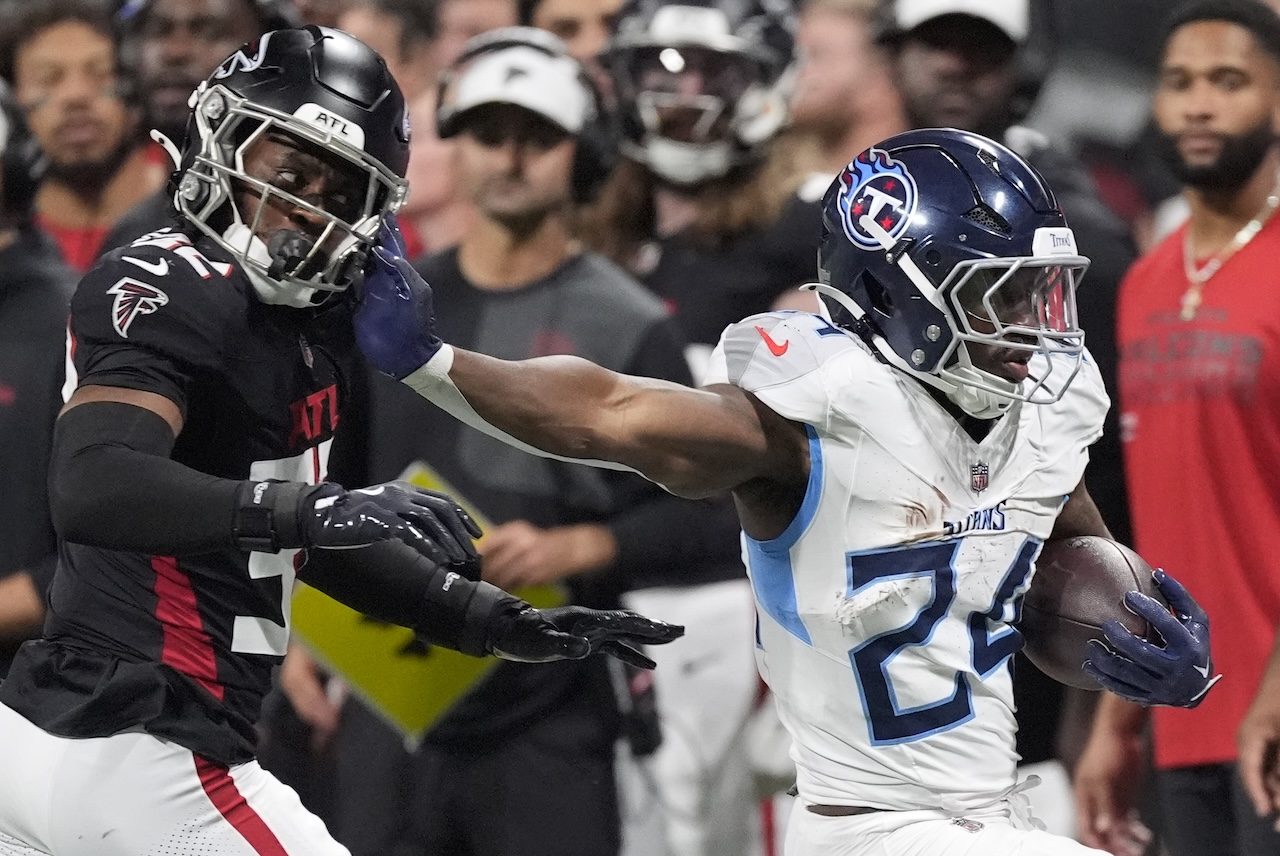 Tennessee Titans running back Jordan Mims (24) runs the ball past Atlanta Falcons safety Henry Black (32) during the second half of a preseason NFL football game, Friday, Aug. 15, 2025, in Atlanta. (AP Photo/Mike Stewart)