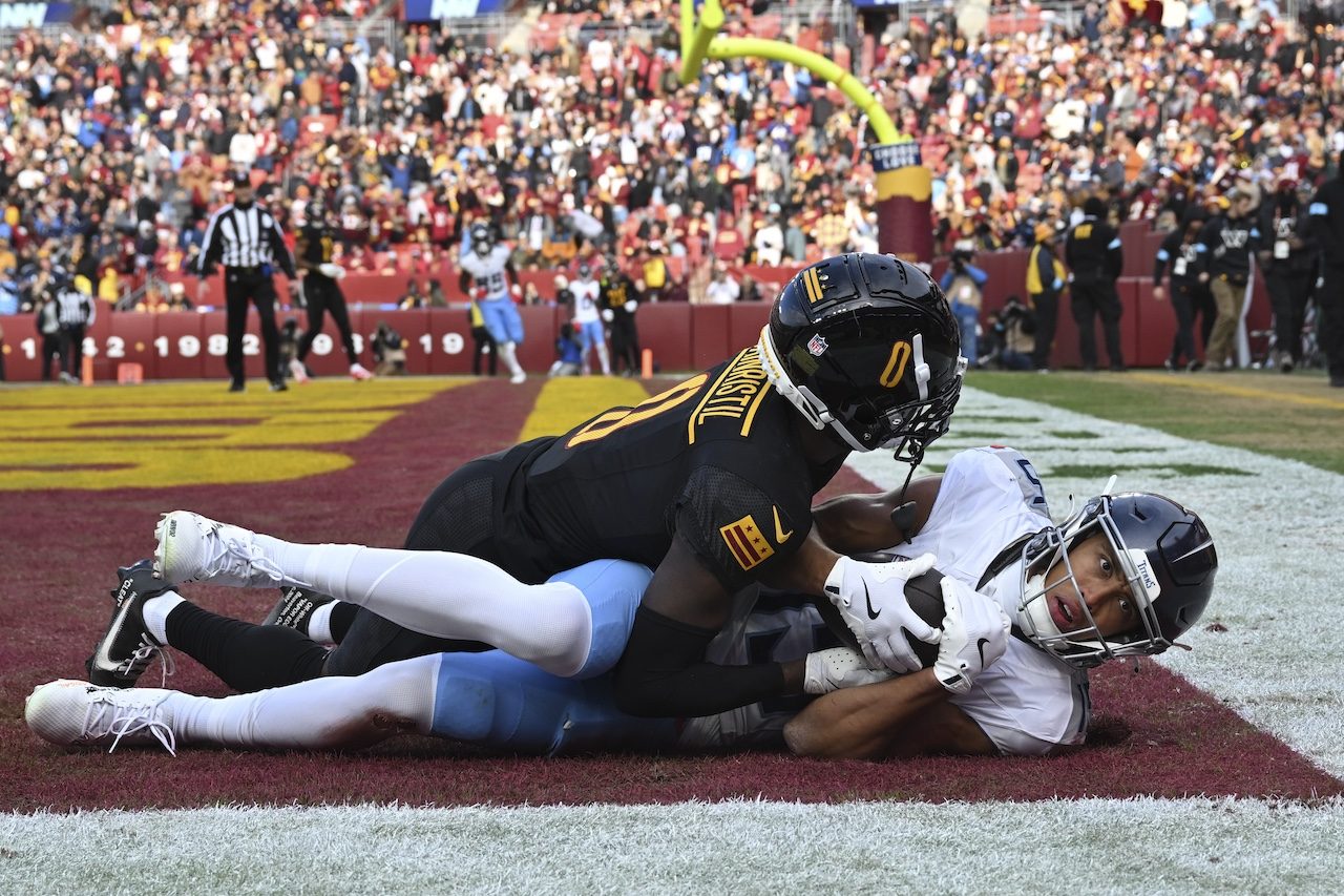 Tennessee Titans wide receiver Nick Westbrook-Ikhine, right, scores a touchdown past Washington Commanders cornerback Mike Sainristil (0) during the first half of an NFL football game Sunday, Dec. 1, 2024, in Landover, Md. (AP Photo/Steve Ruark)