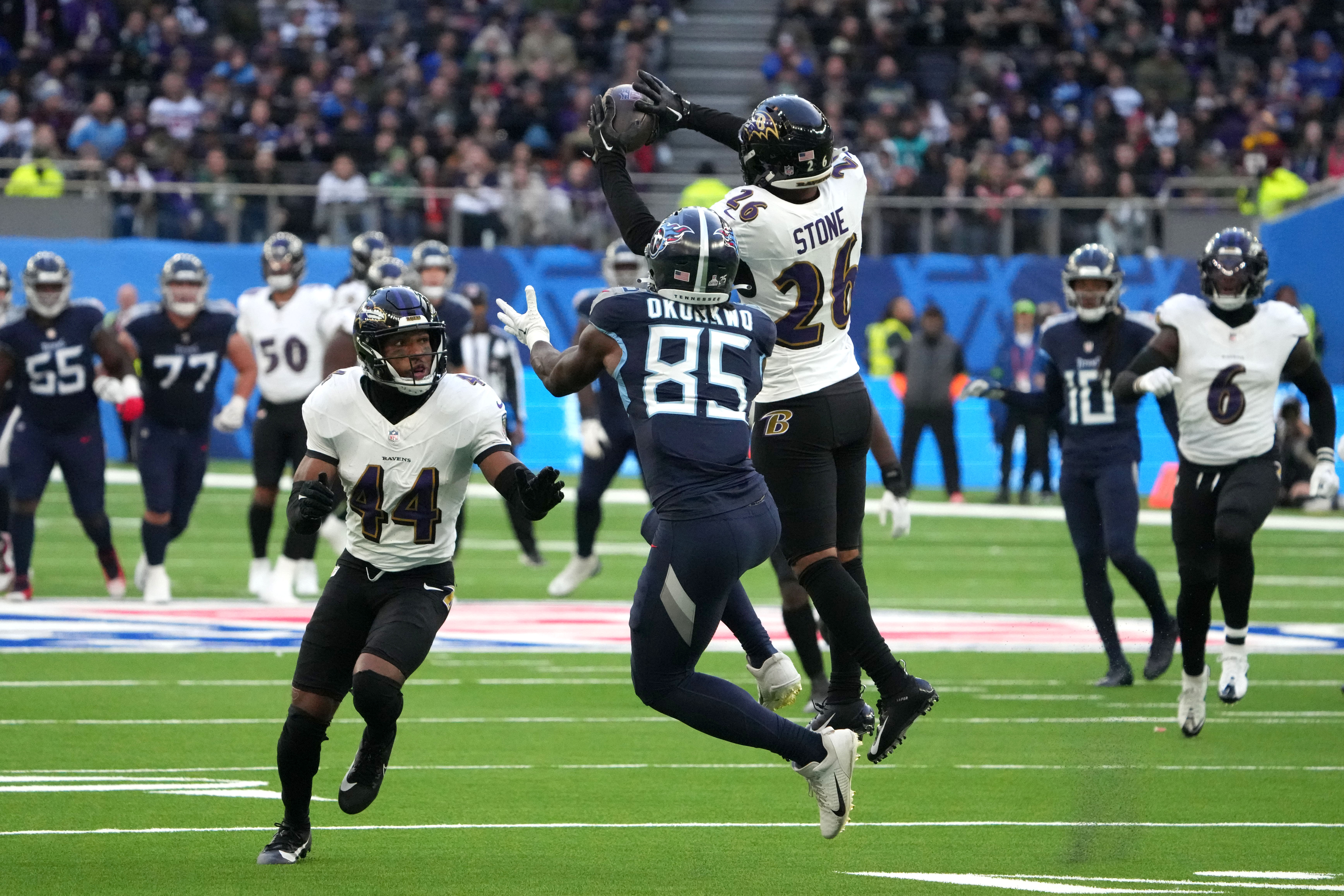 Oct 15, 2023; London, United Kingdom; Baltimore Ravens safety Geno Stone (26) intercepts a pass intended for Tennessee Titans tight end Chigoziem Okonkwo (85) as Ravens cornerback Marlon Humphrey (44) watches in the second half during an NFL International Series game at Tottenham Hotspur Stadium. Mandatory Credit: Kirby Lee-USA TODAY Sports