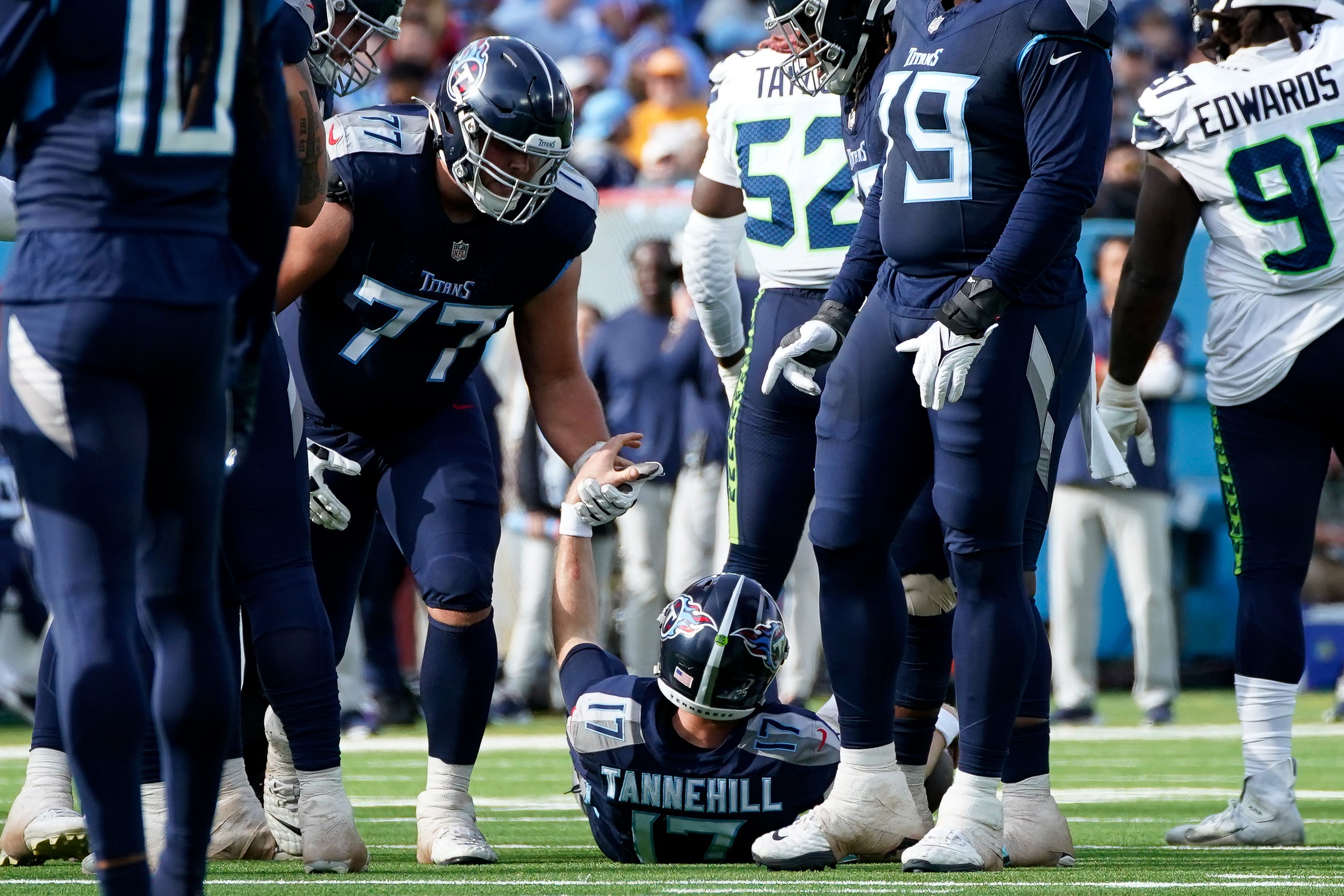 Tennessee Titans offensive tackle Peter Skoronski (77) picks up quarterback Ryan Tannehill (17) after he was sacked by the Seattle Seahawks during the second quarter at Nissan Stadium in Nashville, Tenn., Sunday, Dec. 24, 2023.