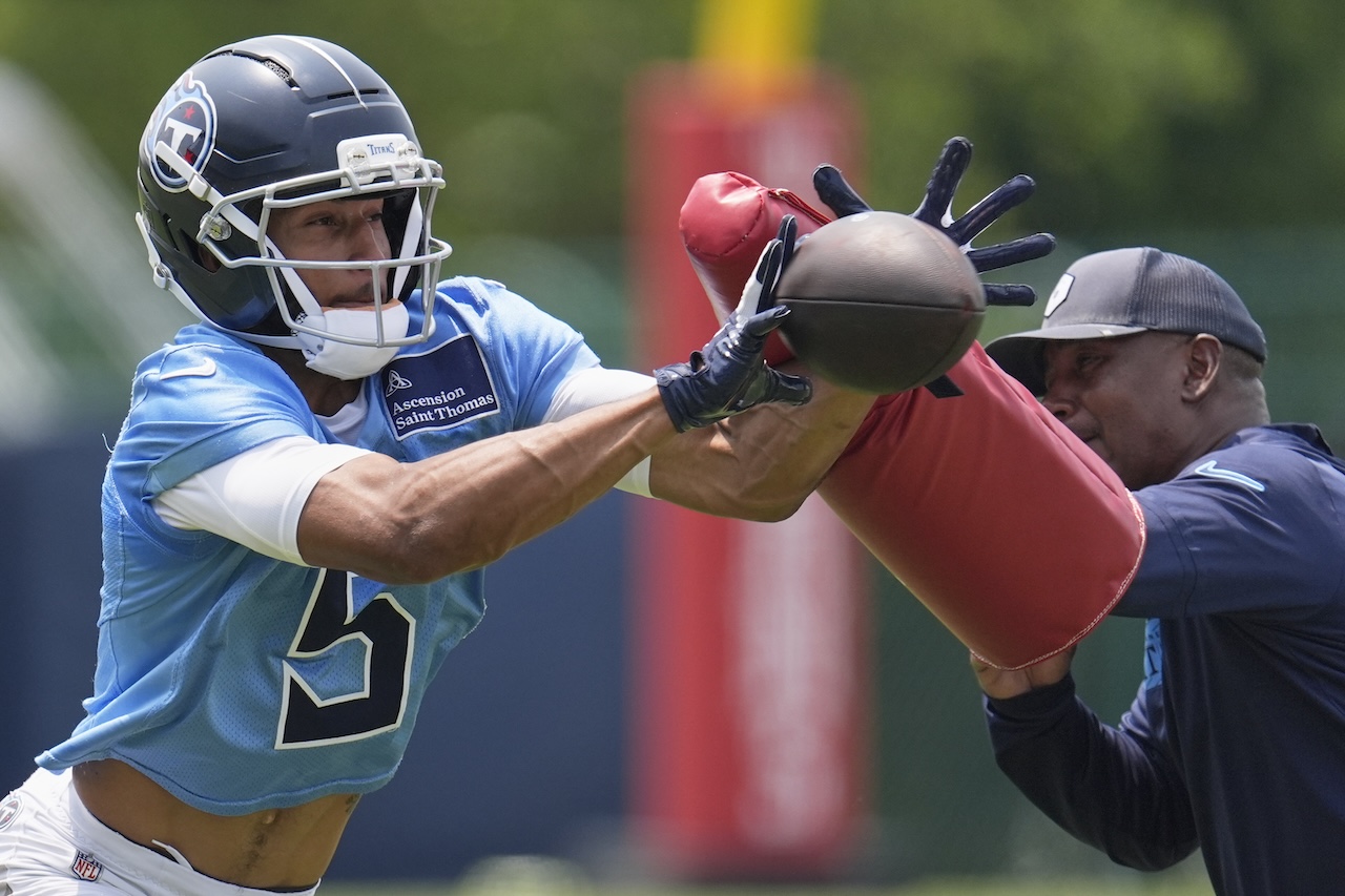Tennessee Titans wide receiver Elic Ayomanor (5) makes a catch past wide receivers coach Tyke Tolbert during practice at NFL football minicamp Tuesday, June 10, 2025, in Nashville, Tenn. (AP Photo/George Walker IV)