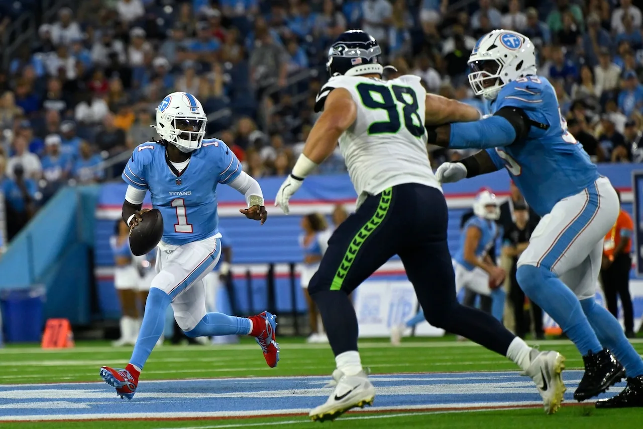 Tennessee Titans quarterback Cam Ward (1) runs from Seattle Seahawks defensive tackle Rylie Mills (98) during the first half of a preseason NFL football game, Sunday, Aug. 23, 2026, in Nashville, Tenn. (AP Photo/John Amis)